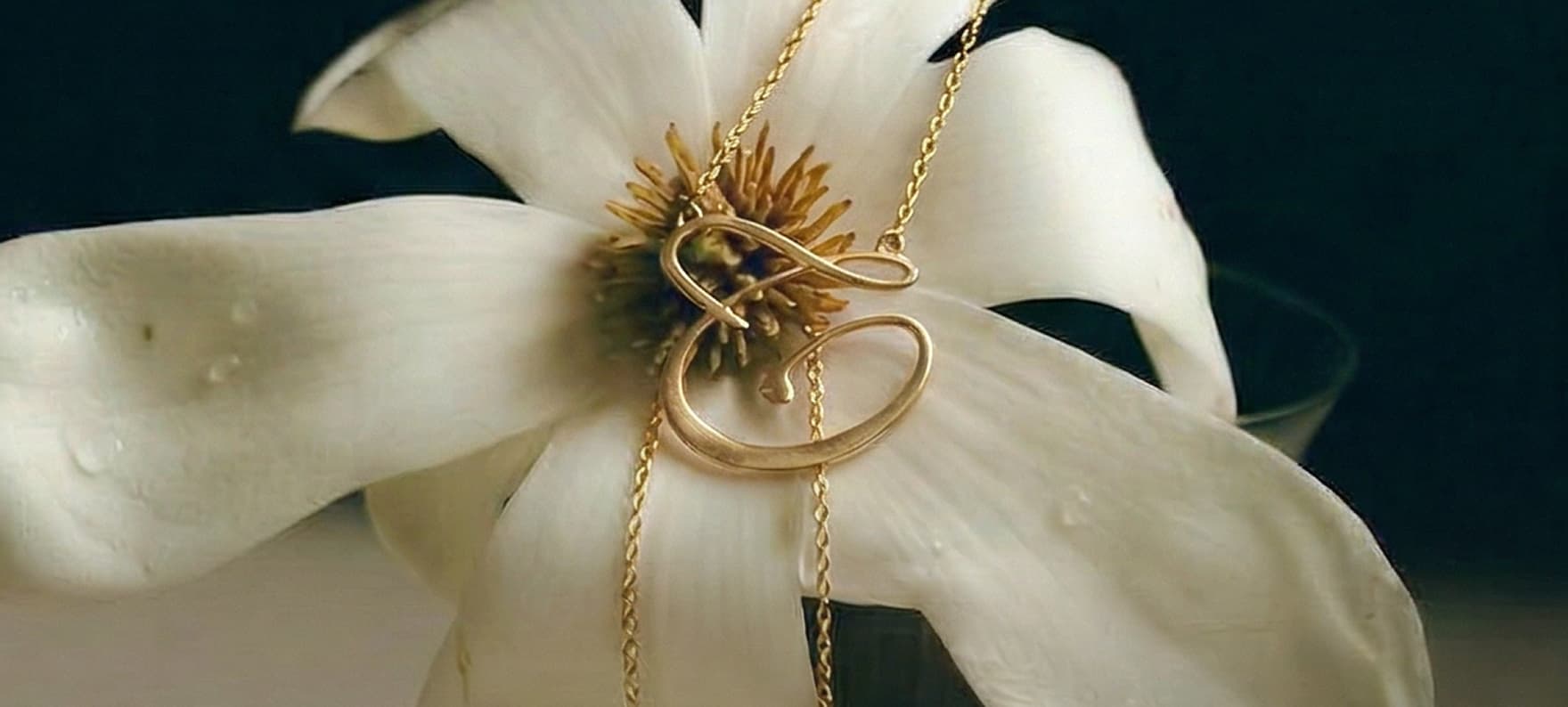 Gold Jourie jewelry arranged over a gardenia flower